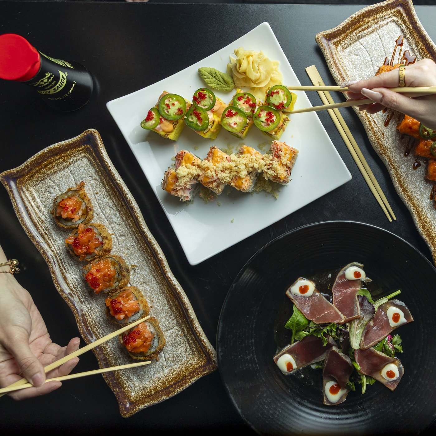 Overhead sushi spread with rolls, tuna tataki and chopsticks, shot for Sushi Lounge